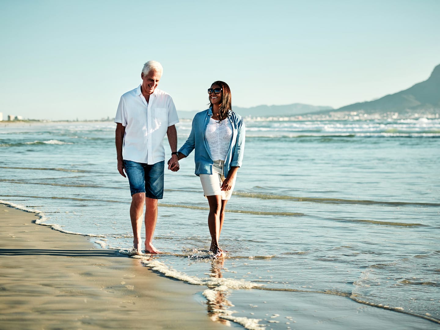 Man and woman walking and holding each other's hand at the beach