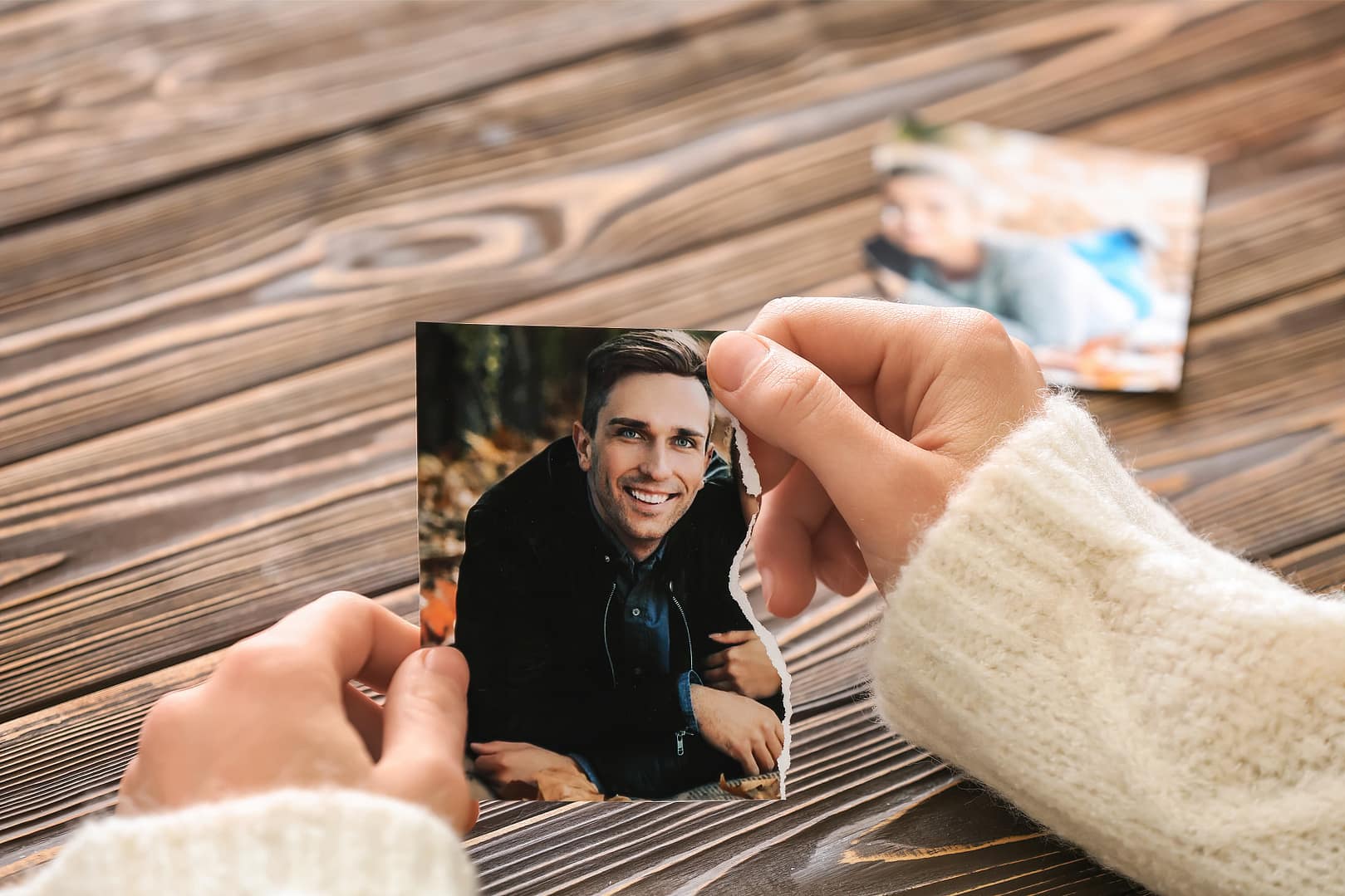 Woman's hand holding her relationship's torn couple's photo