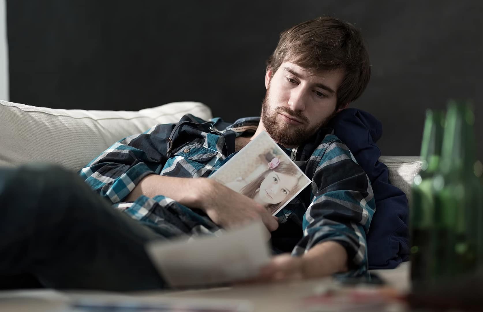 Man thinking about how to get your ex back while holding photo of former girlfriend