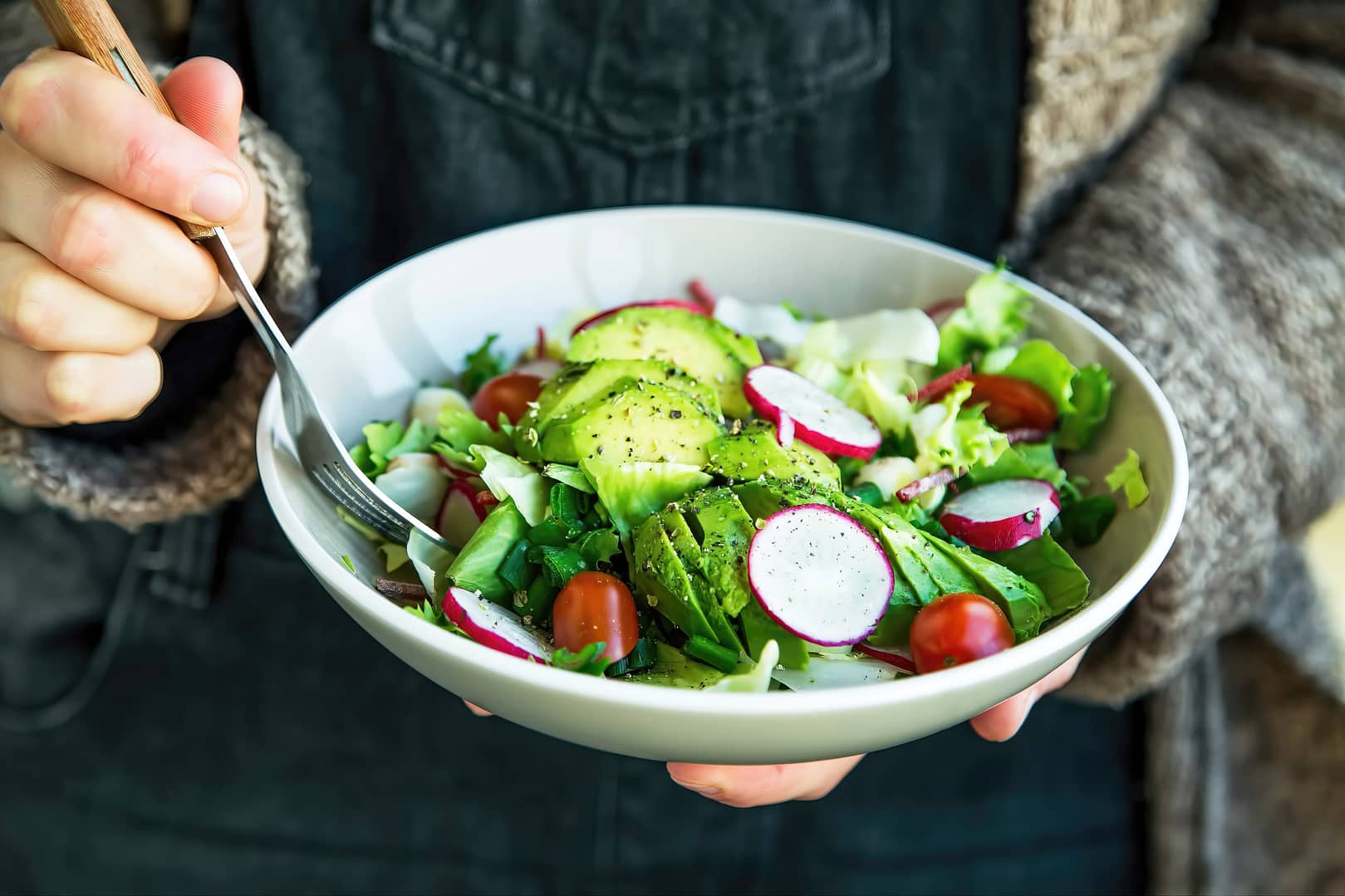 Close-up of a woman holding a bowl of salad bowl