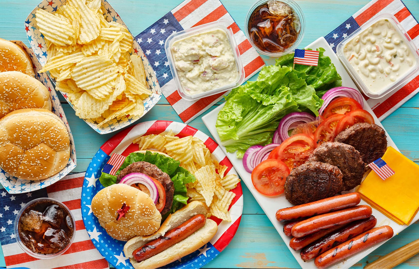 Fourth of july feast with burgers and hot dogs on picnic table