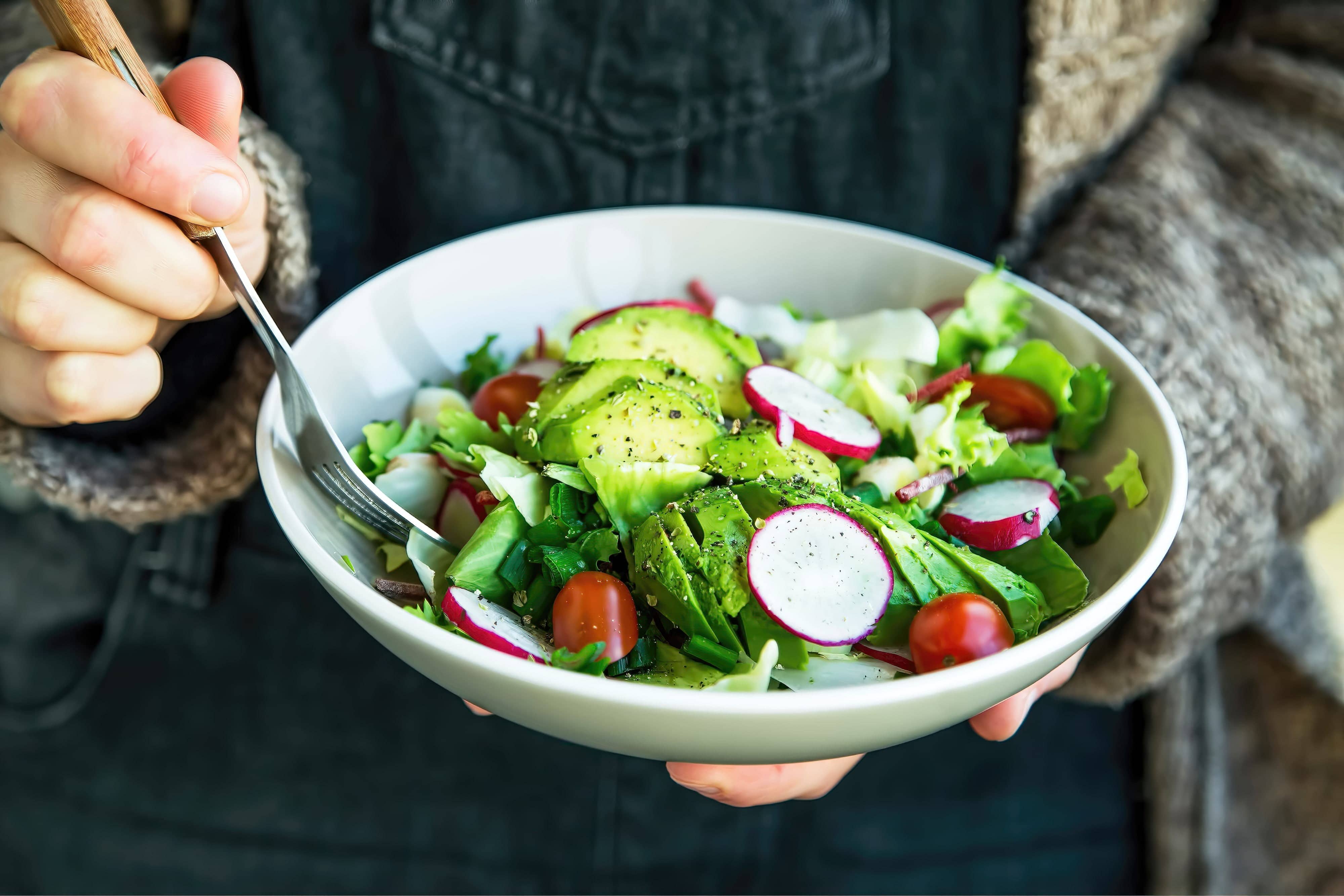 Close-up of a woman holding a bowl of salad bowl
