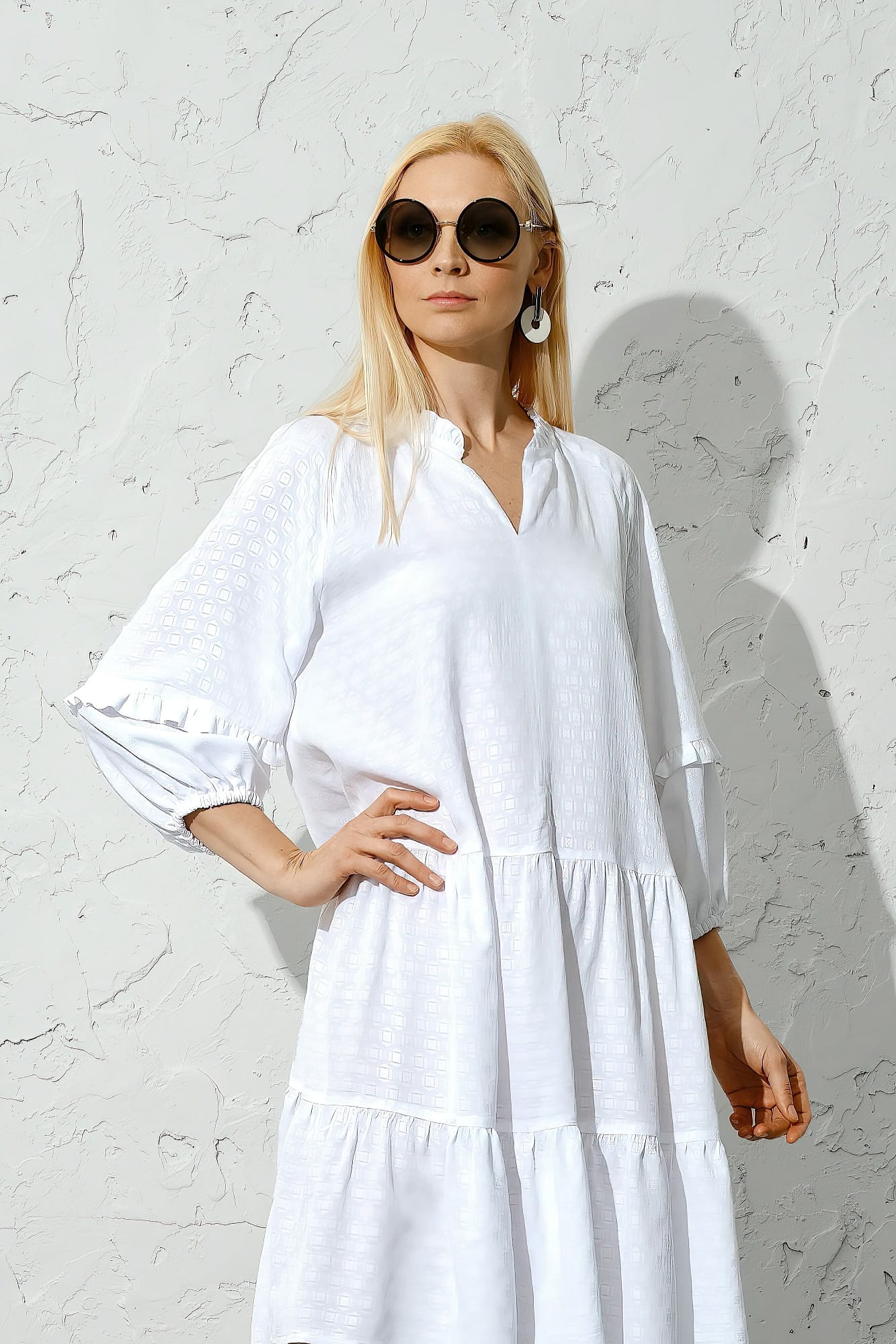 Classy blonde woman in wide white dress posing