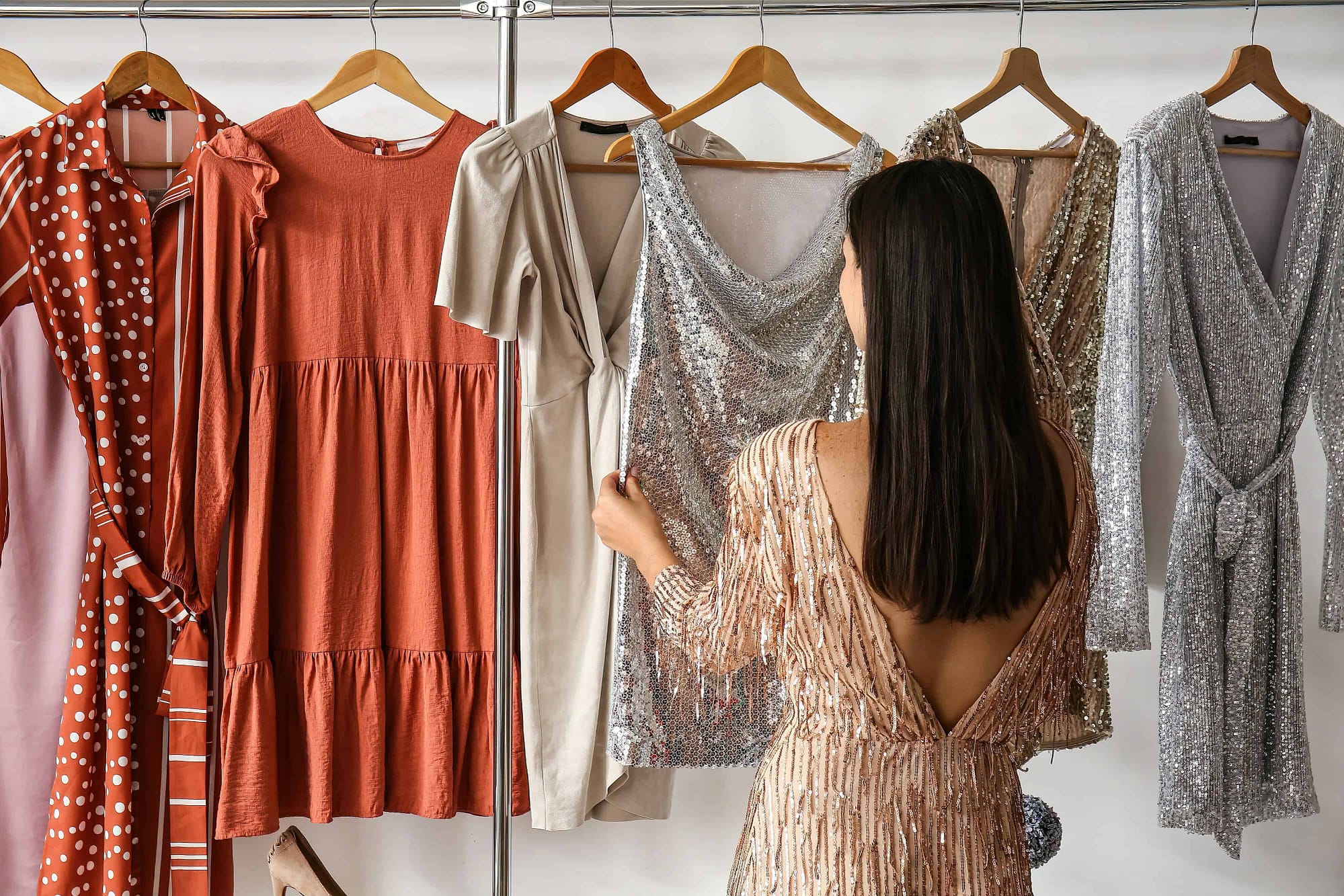 Fashionable woman choosing dress in dressing room
