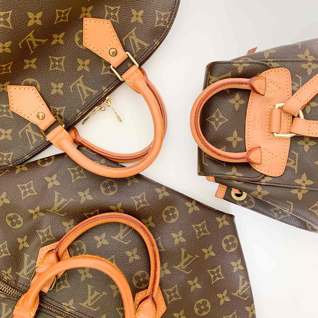 A collection of Louis Vuitton handbags with brown monogrammed canvas and leather handles, displayed on a light surface