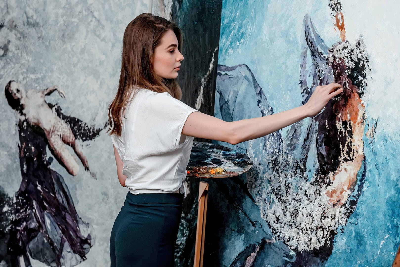 The artist paints abstract oil paintings, working on a painting in a cozy studio Pro Photo