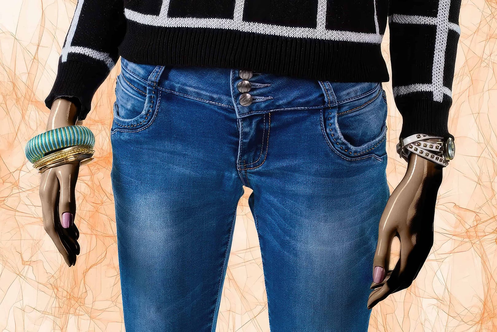 A mannequin dressed in a black and white sweater, low-rise jeans, and wearing assorted bracelets and a watch is shown. The background features a beige and abstract pattern