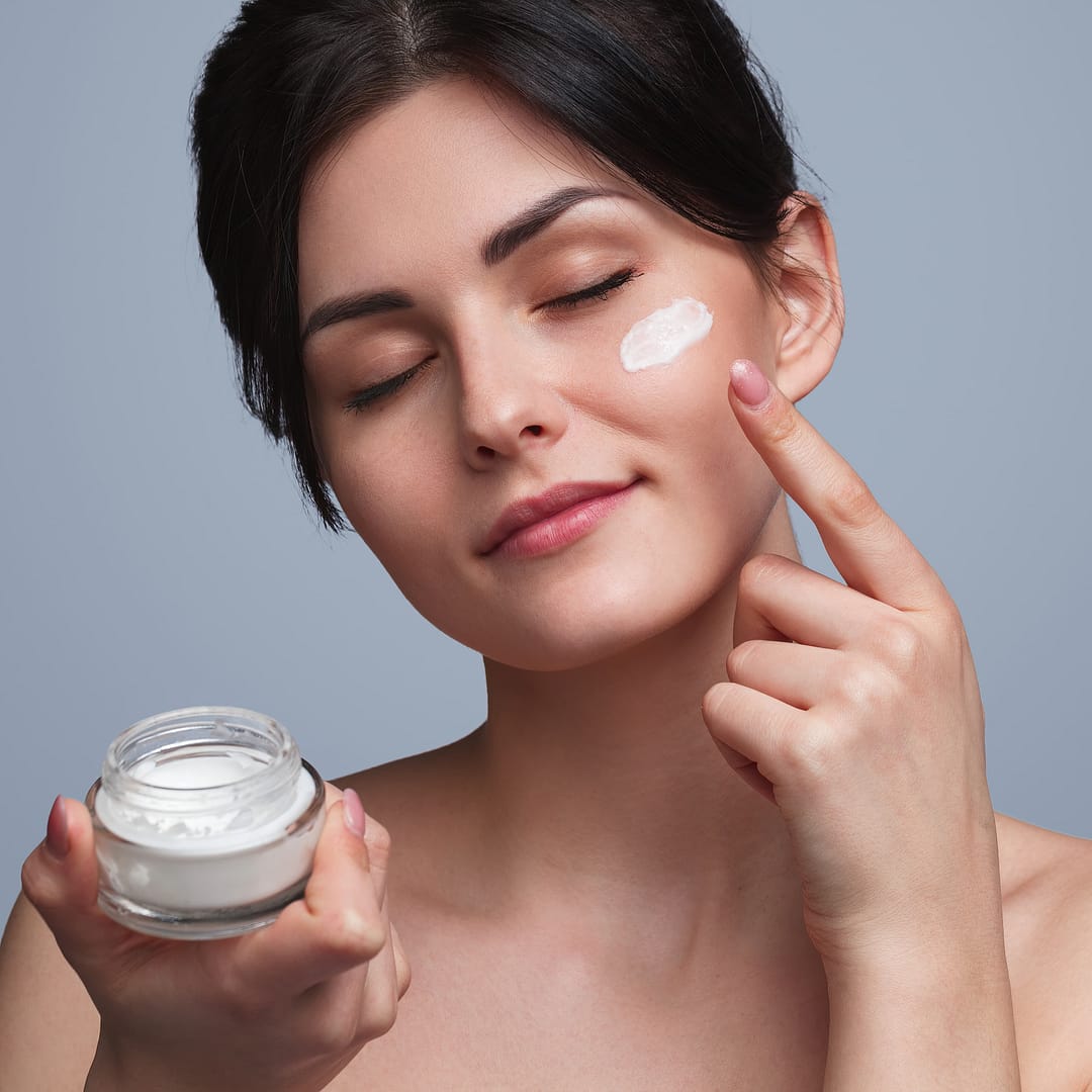 Happy woman applying moisturizing cream