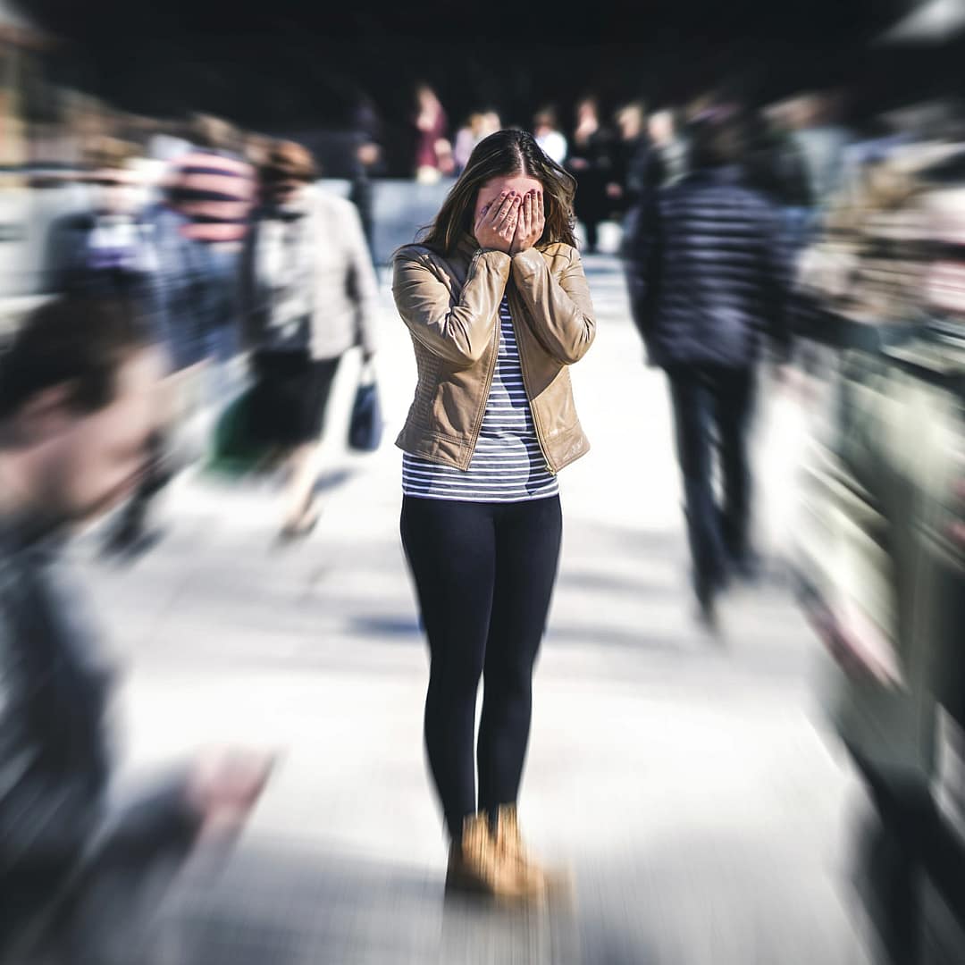 A woman alone standing and feeling less attractive while in a crowd of people