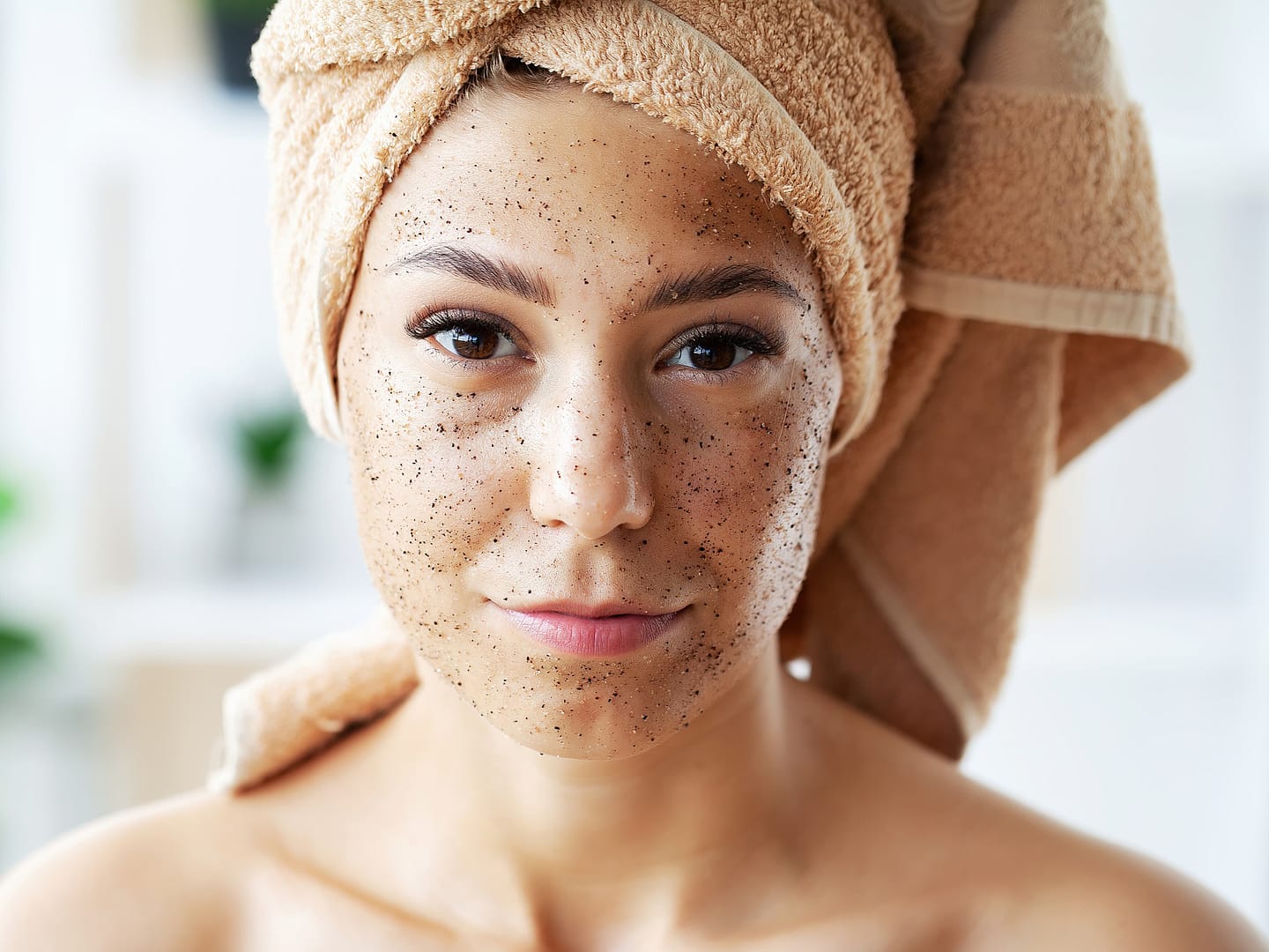 Beautiful young woman with scrub mask in spa salon