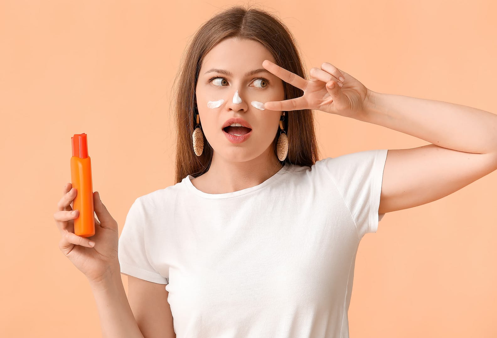 Woman applying sunscreen cream on face