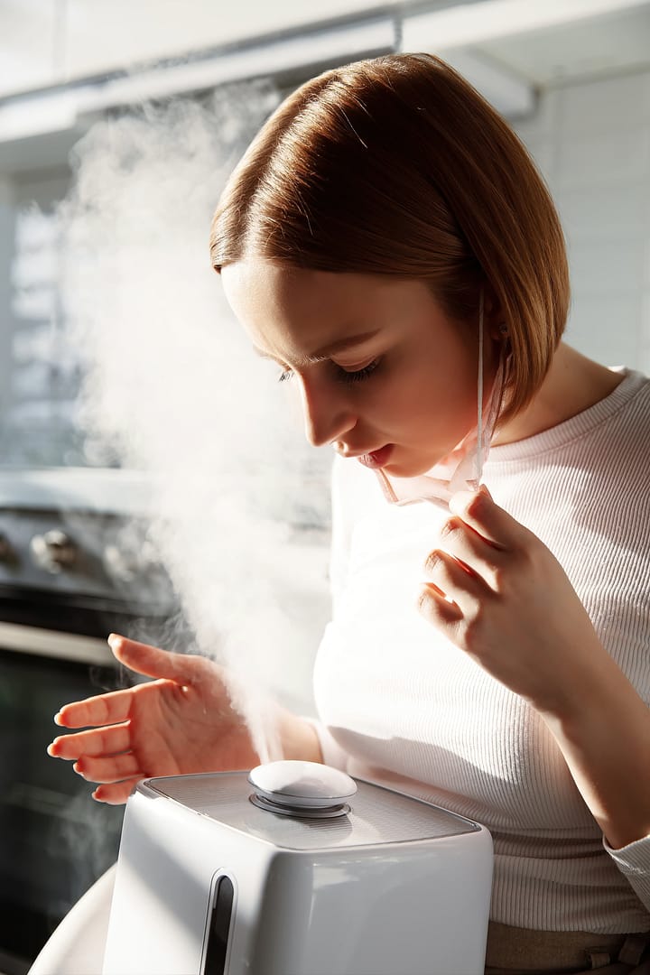Woman using aroma oil humidifier at home