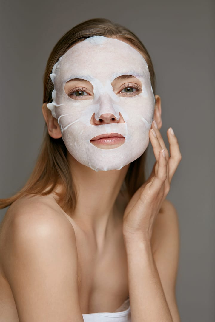 Woman using sheet mask on face skin for spa care