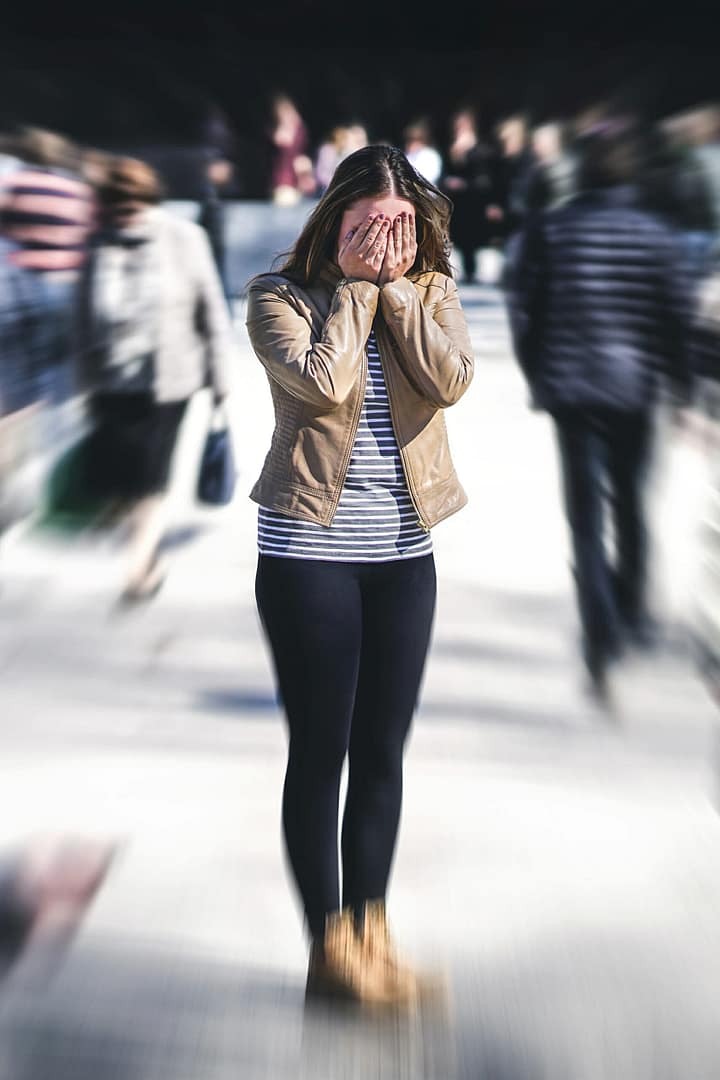 A woman alone standing and feeling less attractive while in a crowd of people