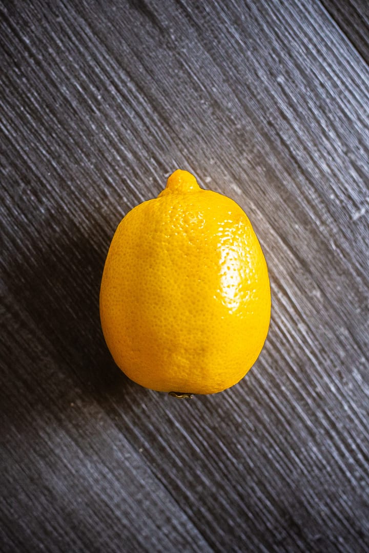 Lemon for glowing skin. A single lemon on a textured gray surface
