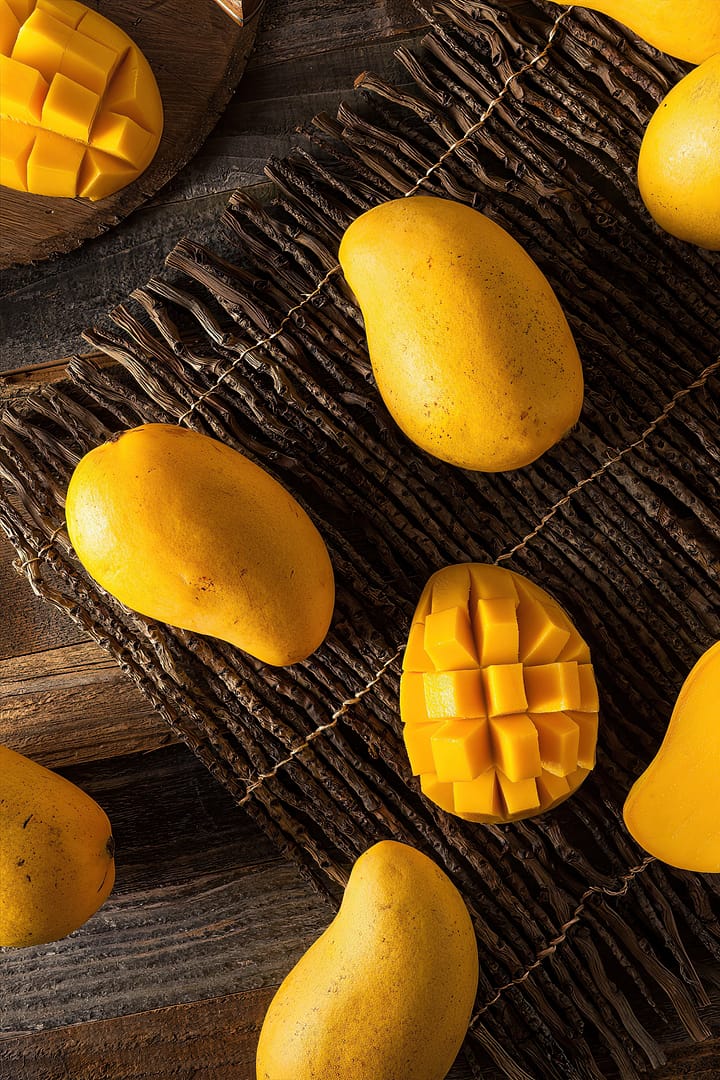 Mango for glowing skin. Whole and diced mangoes arranged on a woven mat