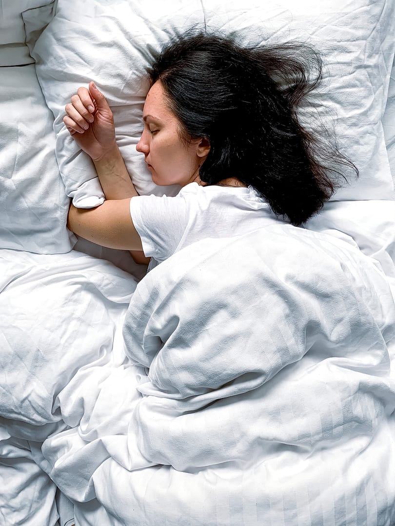 Woman sleeping at home on white bed linen