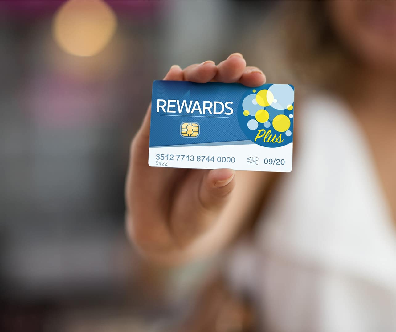 Woman holding a rewards credit card with a blurred background