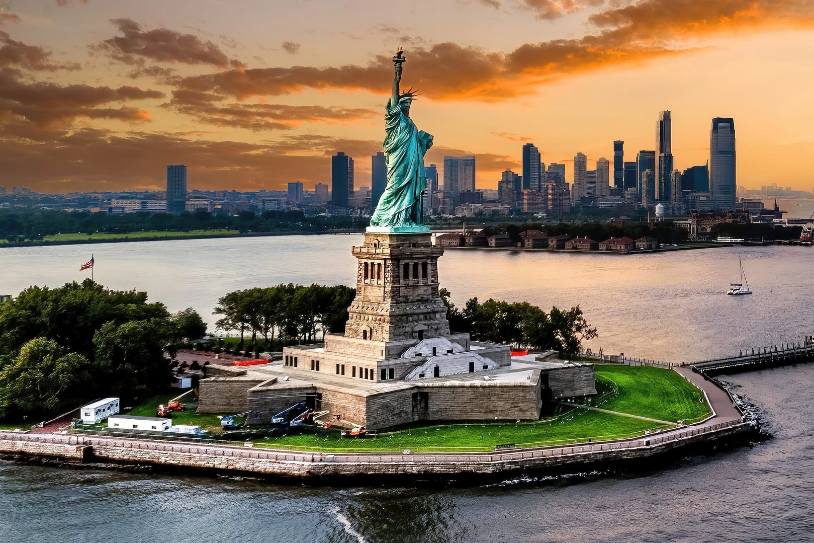 Aerial view of the Statue of Liberty at sunset with the New York City skyline in the background