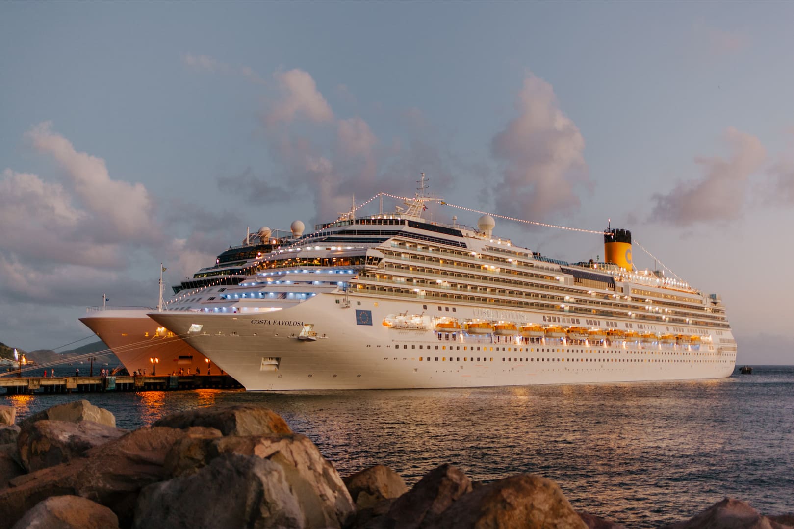 Two white and large Costa Favolosa cruise ships right next to a pier at a port