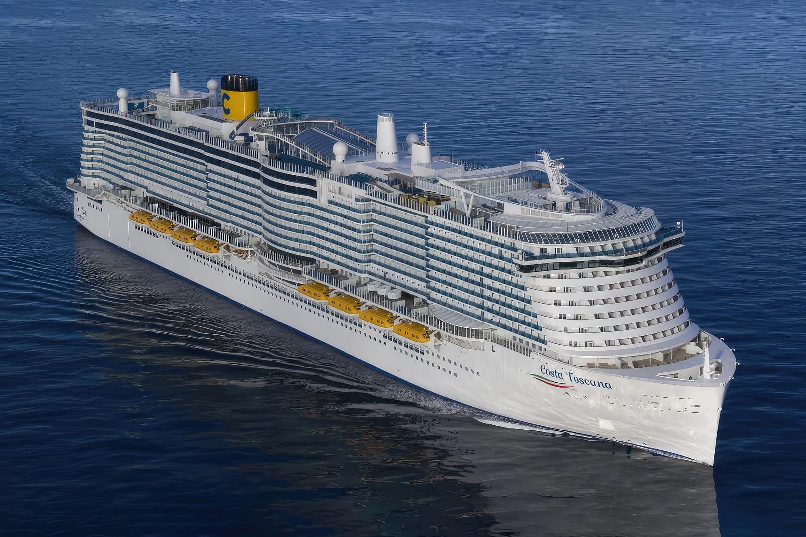 Aerial view of the Costa Toscana cruise ship sailing on blue water, featuring rows of balconies and a yellow funnel