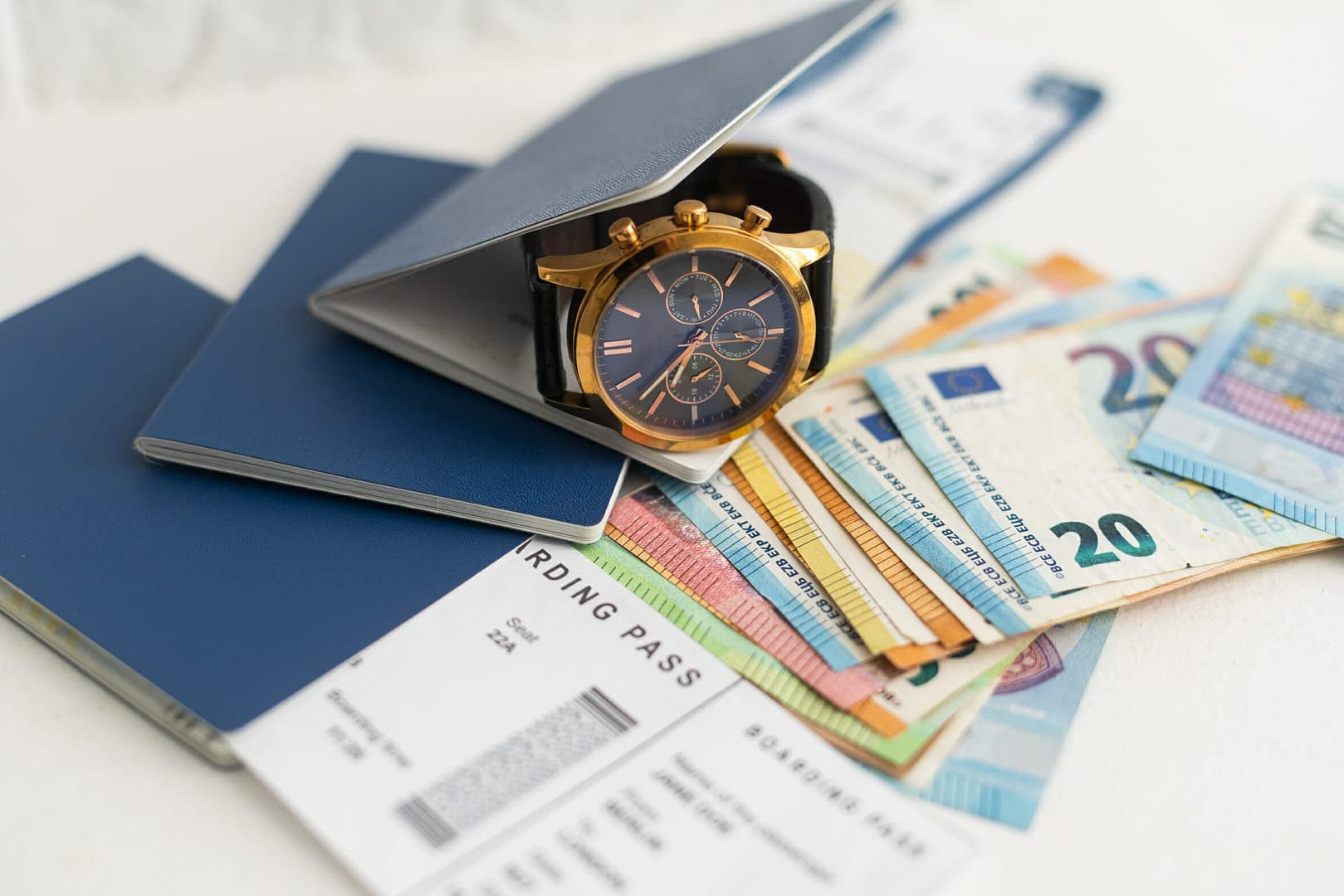 A passport, a flight ticket, differnt currencys on a white surface