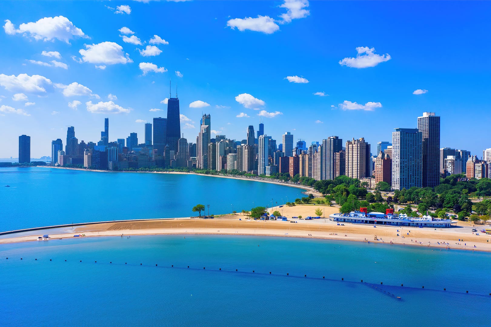 Aerial view of Chicago skyline with tall buildings and North Avenue Beach along Lake Michigan on a clear, sunny day