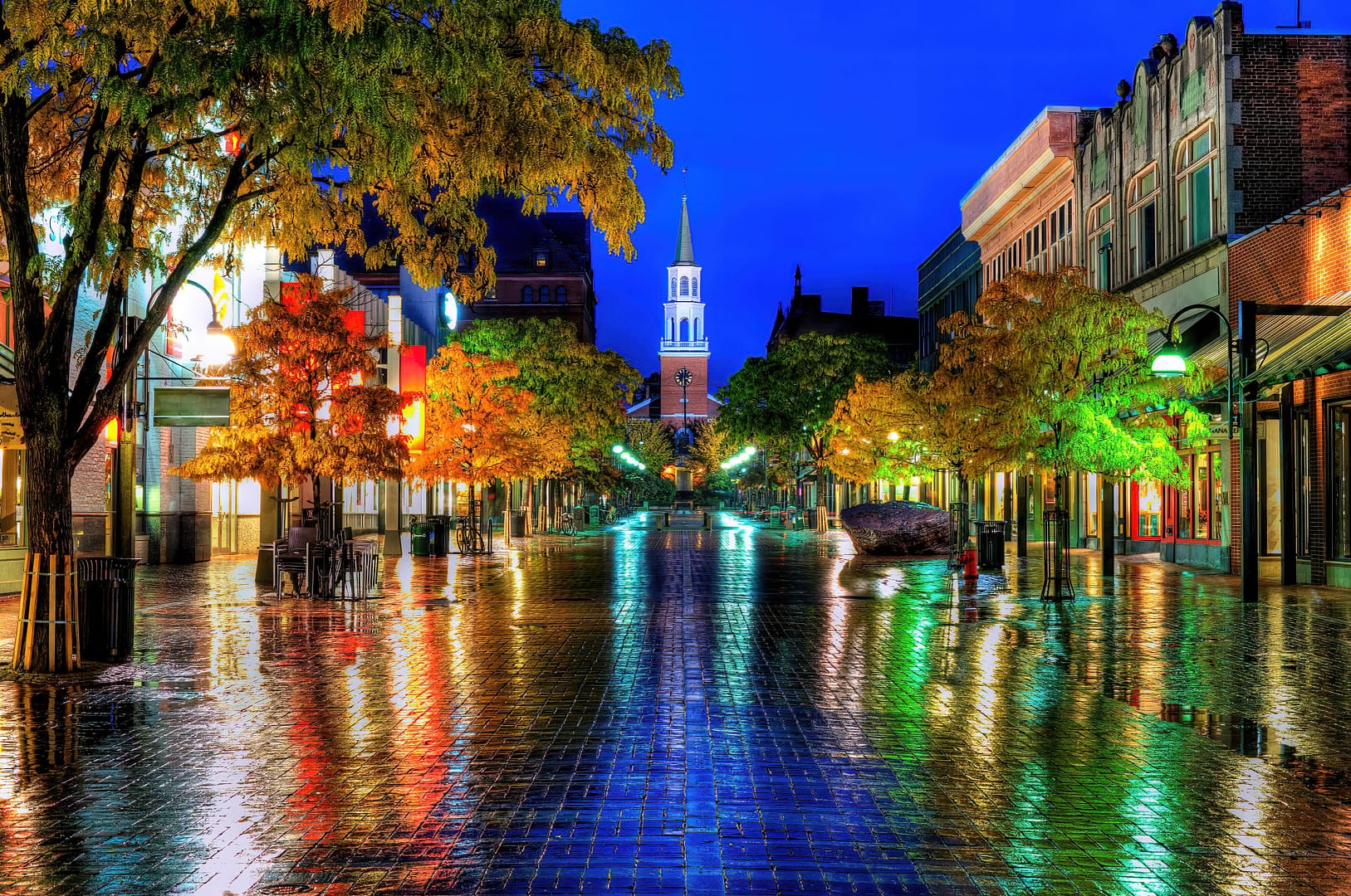 A city street with a church tower in the background, showcasing the urban landscape and religious presence