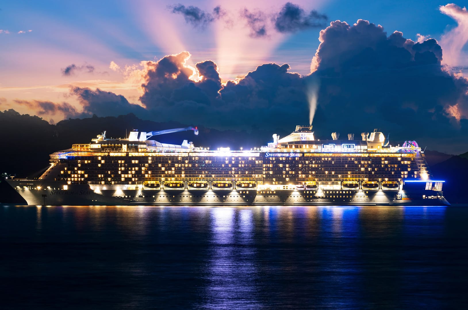 A white and large Spectrum of The Seas luxury cruise ship at sunset