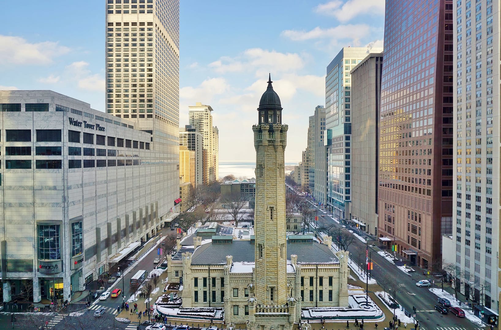 Aerial view of the historic Chicago Water Tower surrounded by modern skyscrapers on a sunny day in an urban setting