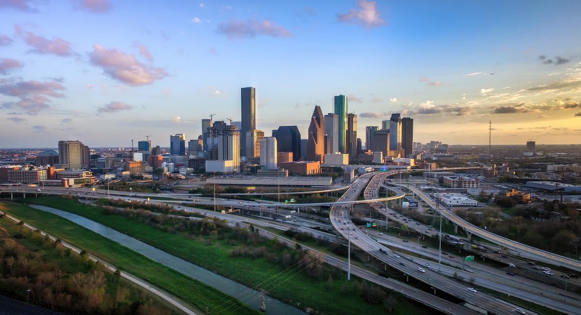 Aerial view of Houston's bustling city skyline at sunset with major highways and lush green areas visible