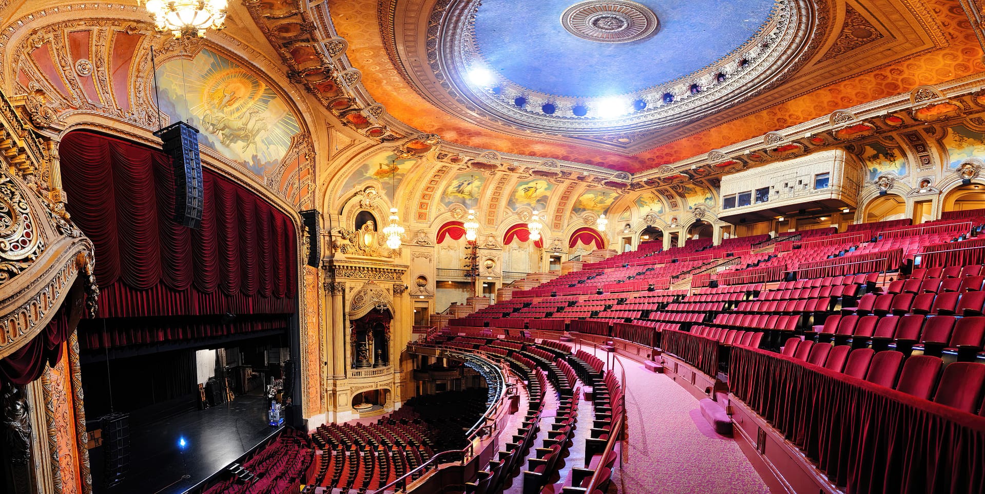 Interior of the Chicago Theatre with red seats, intricate golden decorations, and a blue domed ceiling
