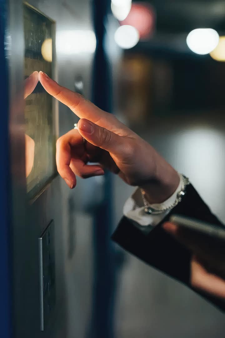 A woman in a business suit tapping a touch screen of an airline ticket machine