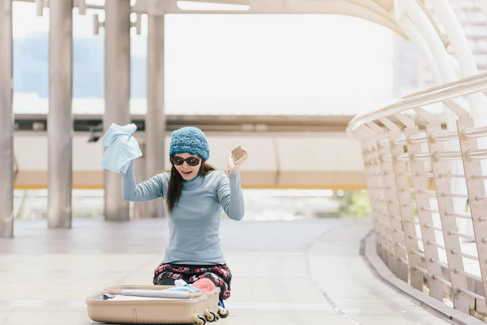 Young woman sitting in airport, looking for something in luggage, forgotten or stolen