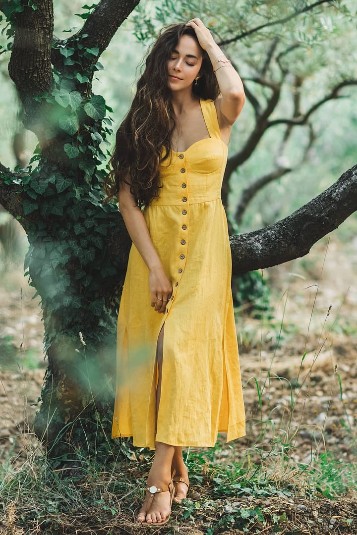 A woman wearing a vibrant yellow dress stands gracefully