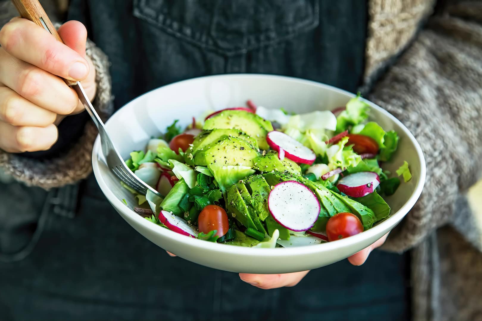 Close-up of a woman holding a bowl of salad bowl