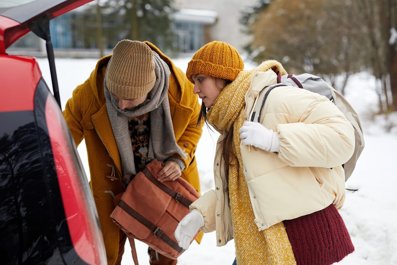 Side view portrait of young couple unloading car trunk in winter while traveling for Christmas holidays