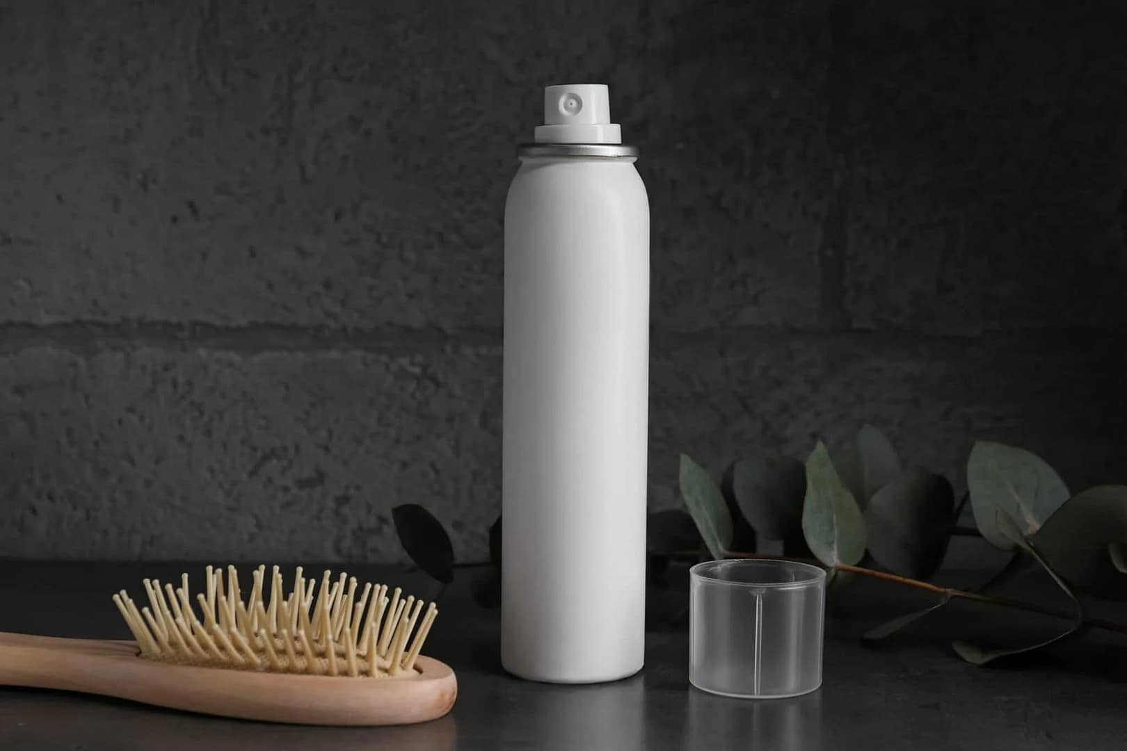 A brush and a bottle of hair spray placed side by side on the table