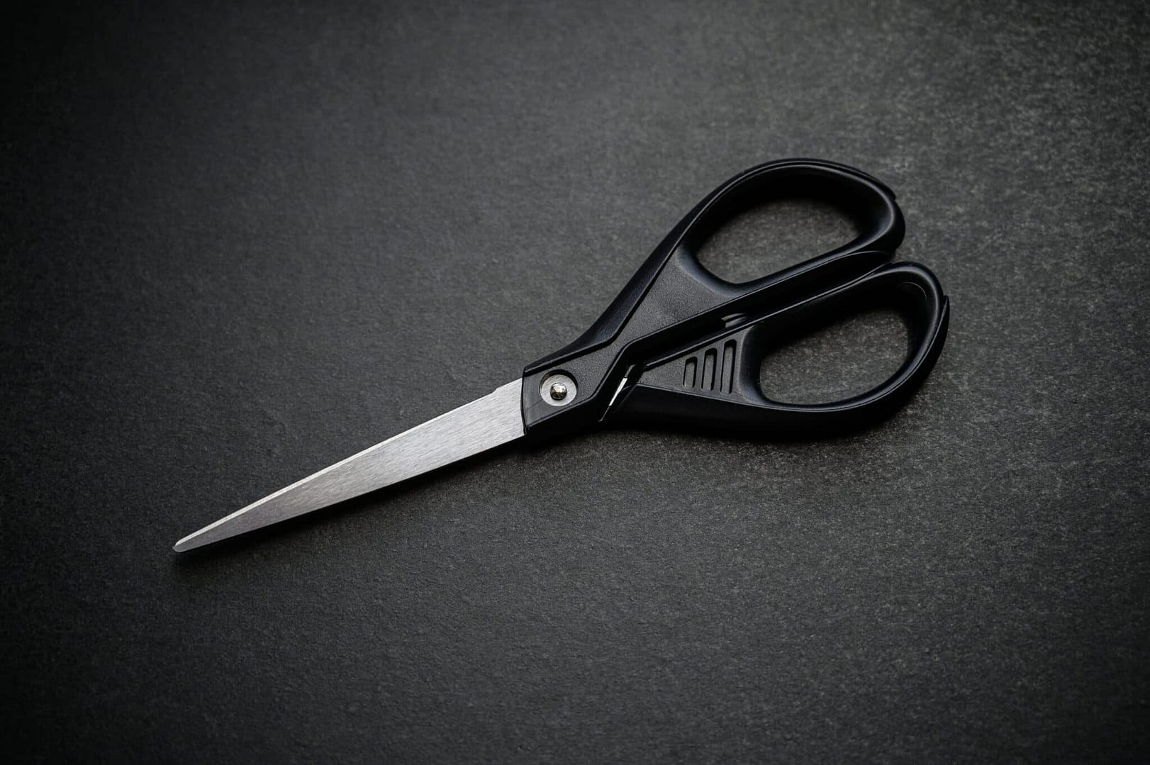 Black scissors placed on a smooth black surface